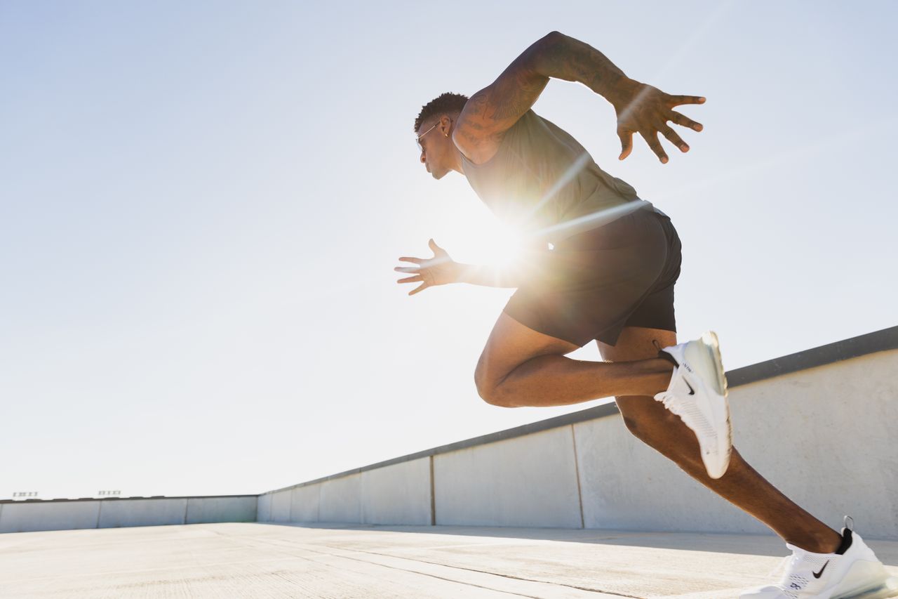 Dynamic side profile of an athletic man sprinting on a rooftop in Austin, Texas at sunrise.