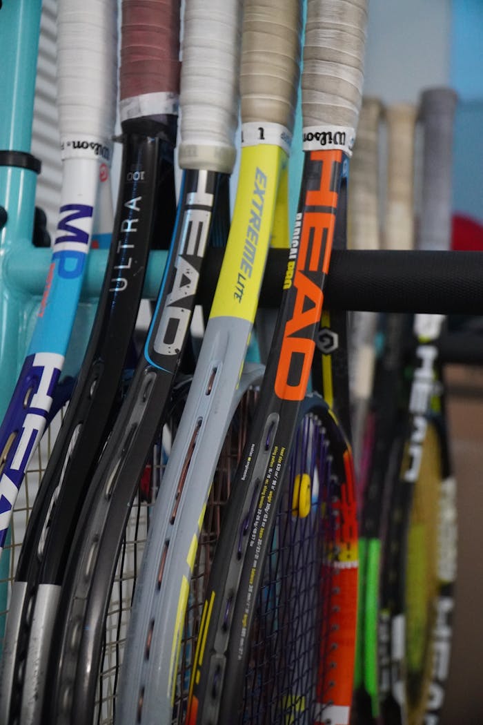 ours-journey A close-up of various tennis rackets stacked closely together indoors.