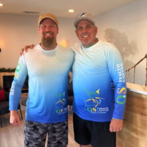 Two men in matching shirts smiling.
