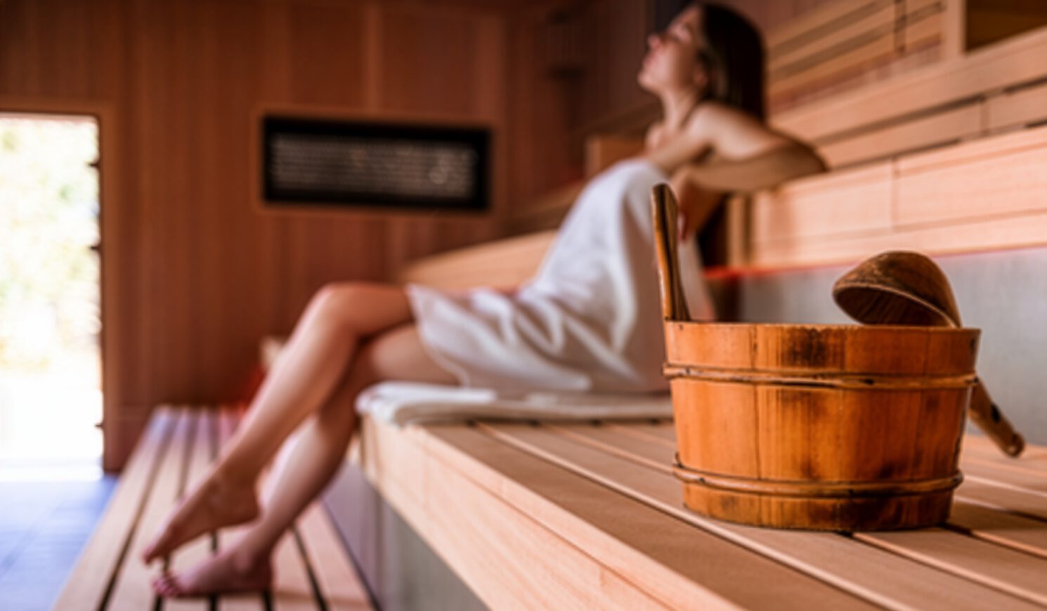 Woman relaxing in a wooden sauna.